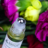 fragrance roller oil scent roller perfume bottle by brigid trading company llc jojoba oil, castor oil, essential oils only aromatherapy clean ingredients amber bottles with flowers in the background celtic holidays scents clean roller bottle close up metal ball